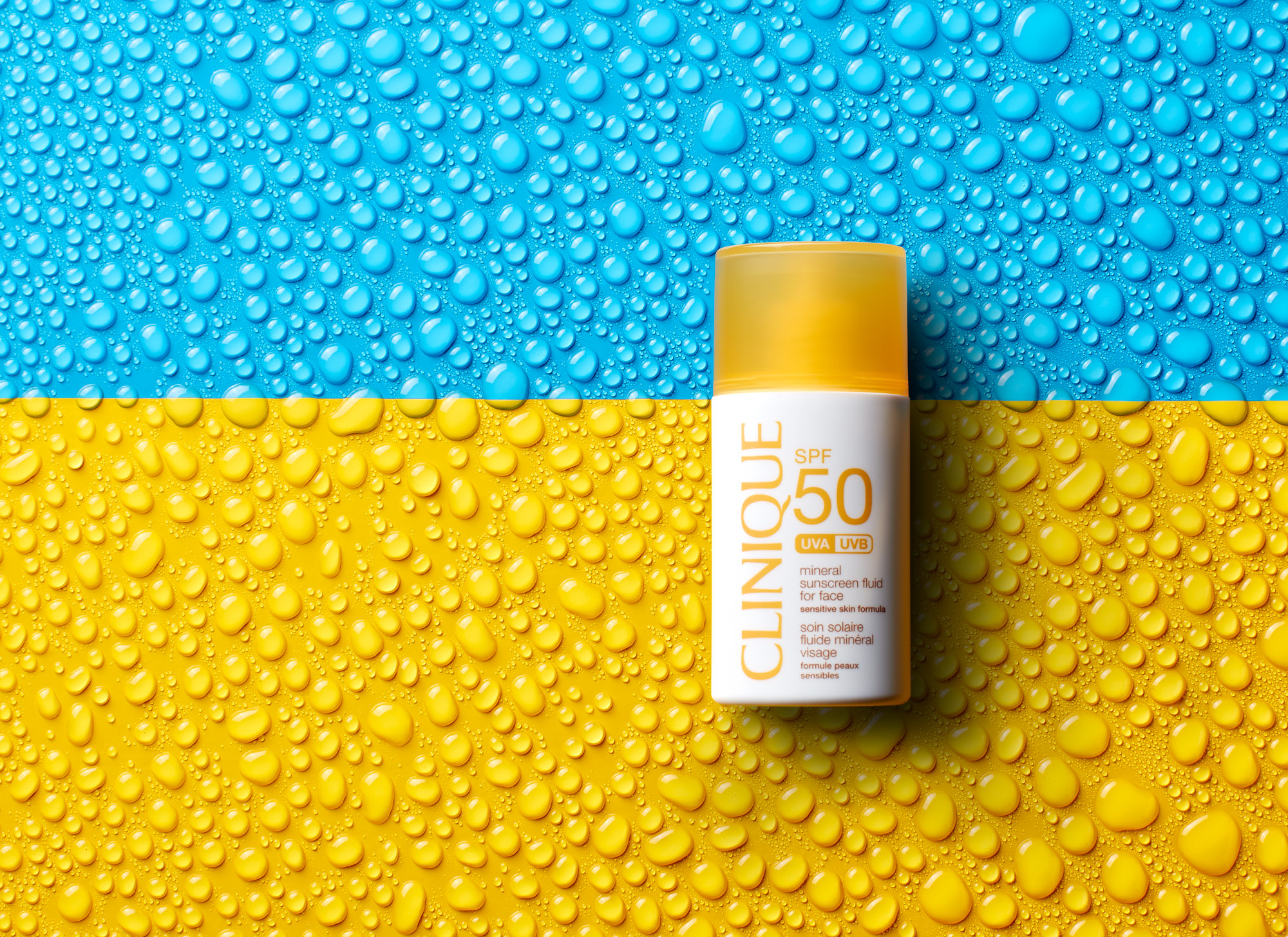 Clinique waterproof sunscreen on color blocked background with water droplets.