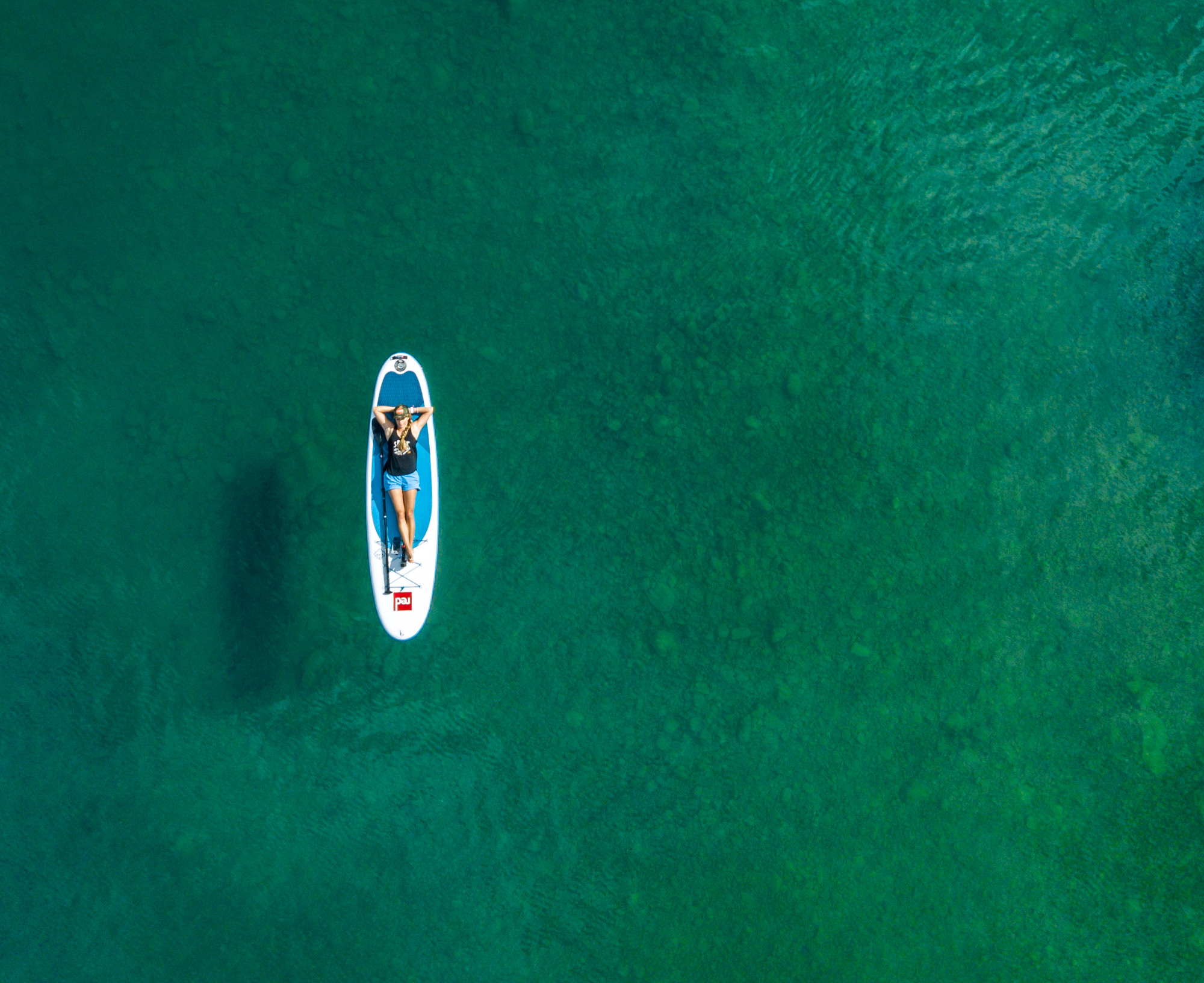 Active lifestyle Aerial drone  photo of girl lying on Red Paddle Company SUP in Lake Chelan, Washington.