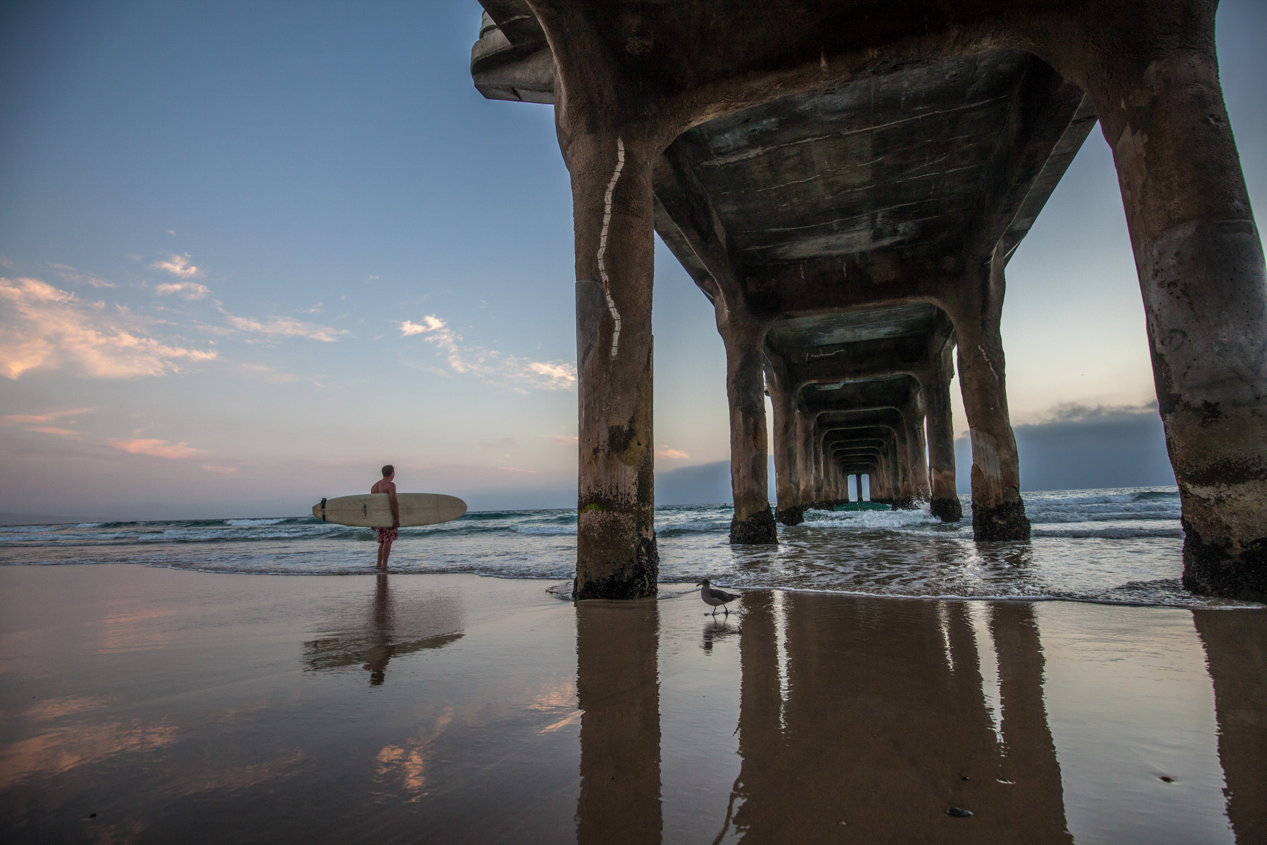 Lifestyle photo of longboard surfer about to paddle out near Huntington Pier in California.