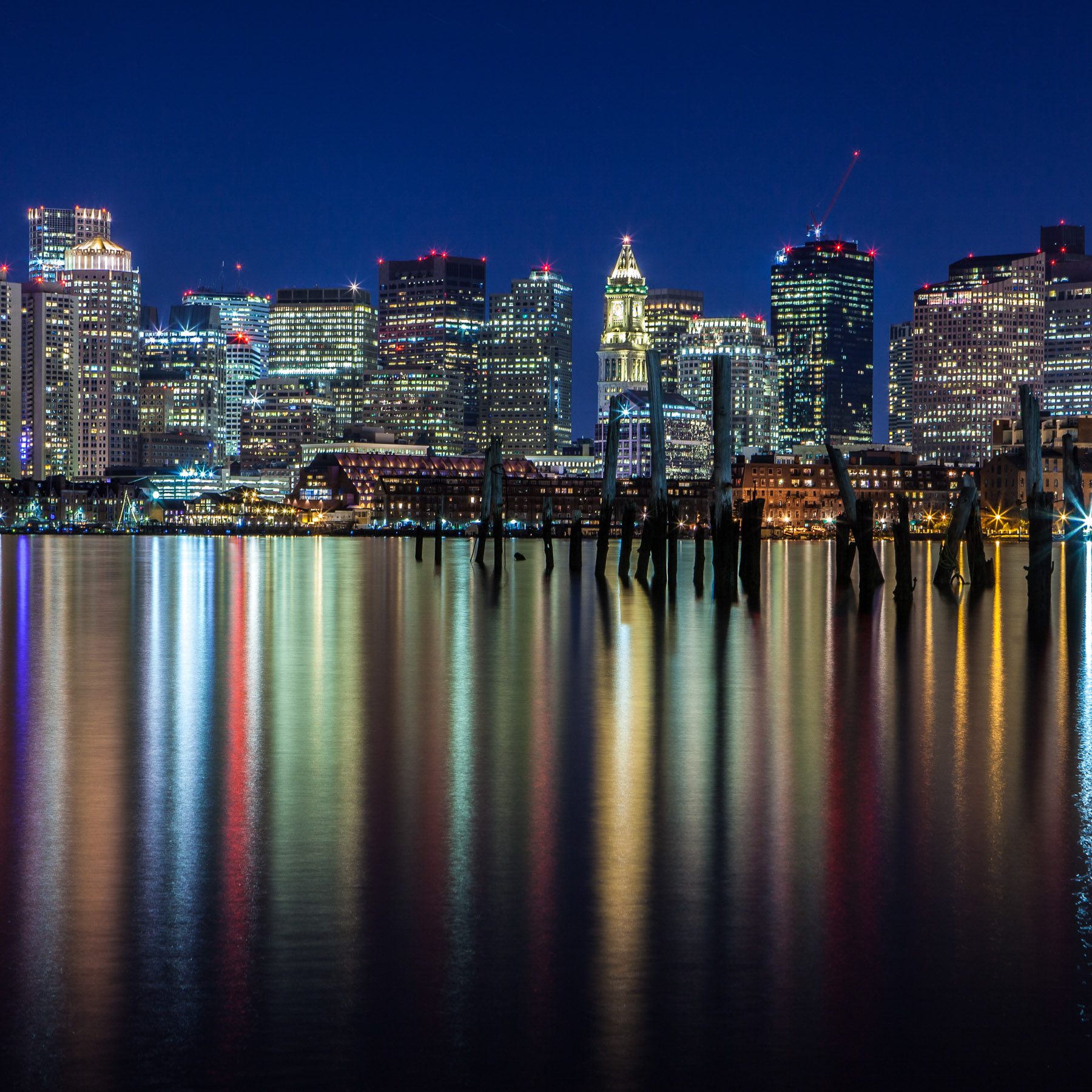 Boston skyline at night reflecting lights of the buildings.