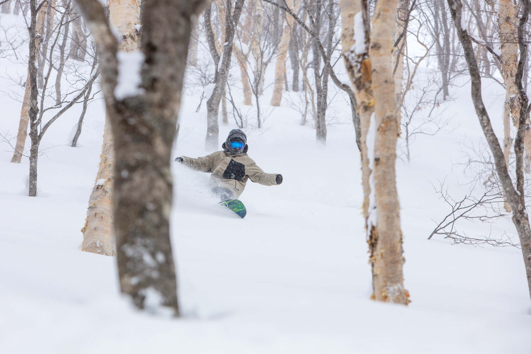 Man snowboarding through the trees in Myoko-Kogen in Japan